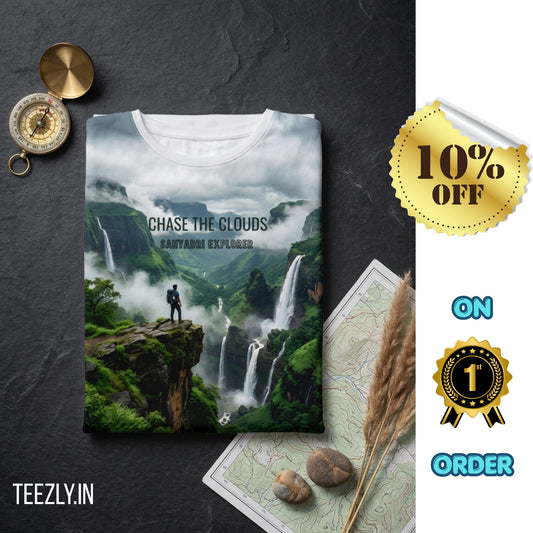 T-shirt with a mountain landscape design and 'Chase the Clouds' text on a dark surface with decorative items.