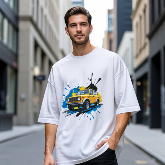 Man wearing a white oversized t-shirt with a graphic design of a yellow car on a city street.