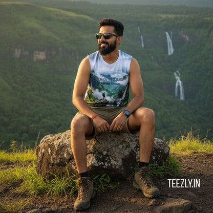 Man sitting on a rock with a scenic view of green hills and waterfalls in the background