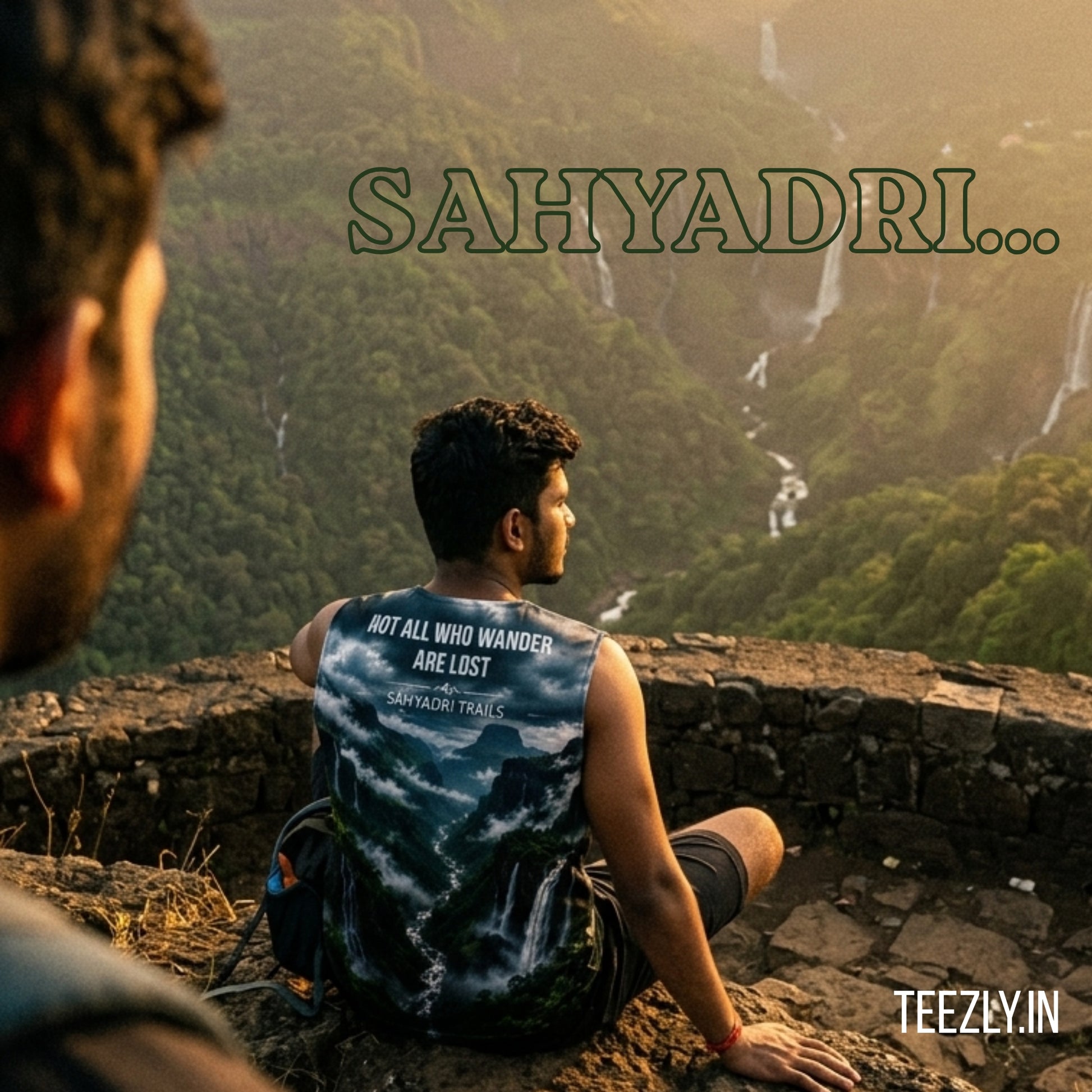 Person sitting on a rocky outcrop overlooking a lush green valley with 'Sahyadri' text.
